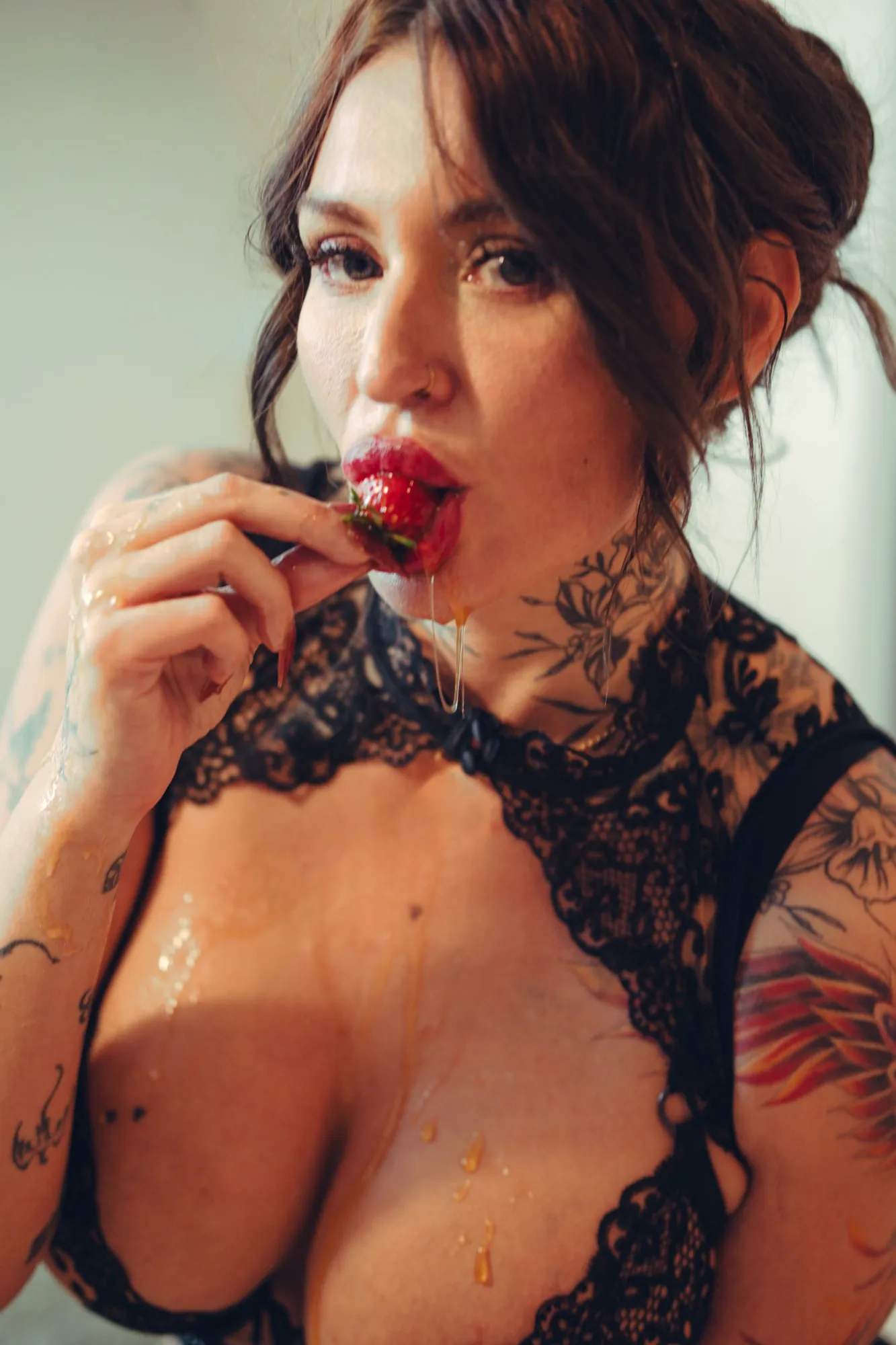 Close-up of Lola biting a honey-dipped strawberry and holding the camera’s gaze
